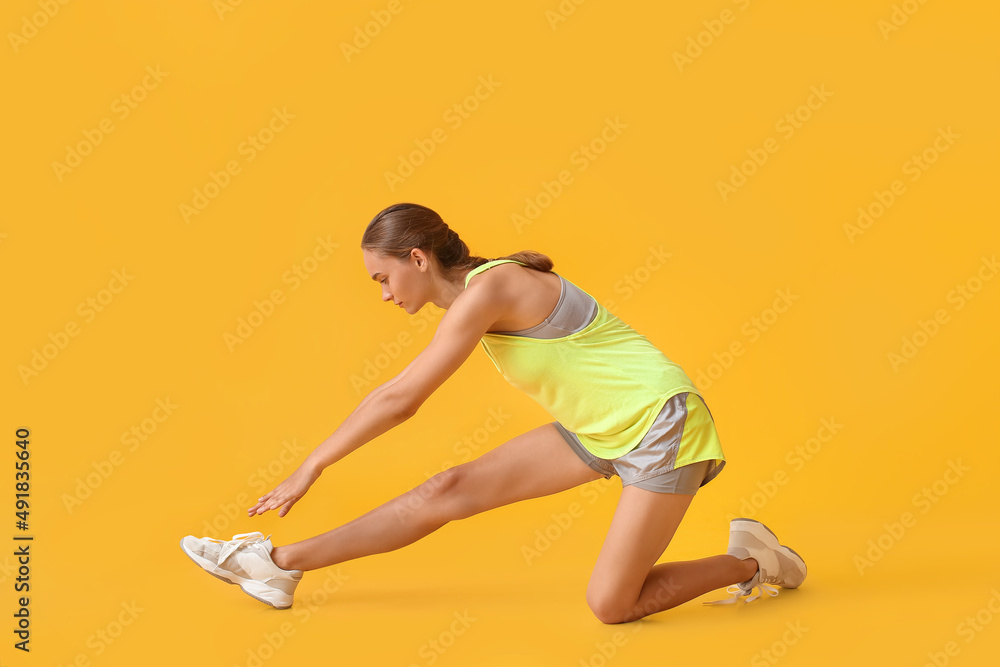 Naklejka premium Sporty young woman exercising on yellow background