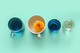 Cups of tasty blue tea and flowers on color background