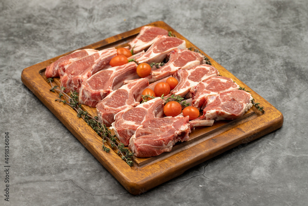 Lamb chops on dark background. Raw lamb chops on wood serving board Lamb chops on dark background. Raw lamb chops on wood serving board