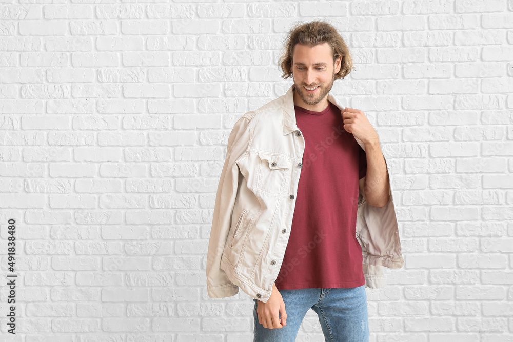Handsome young man in stylish clothes on white brick background Handsome young man in stylish clothes on white brick background