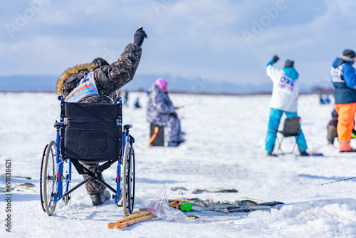 disabled person sitting in a wheelchair catching fish on the ice