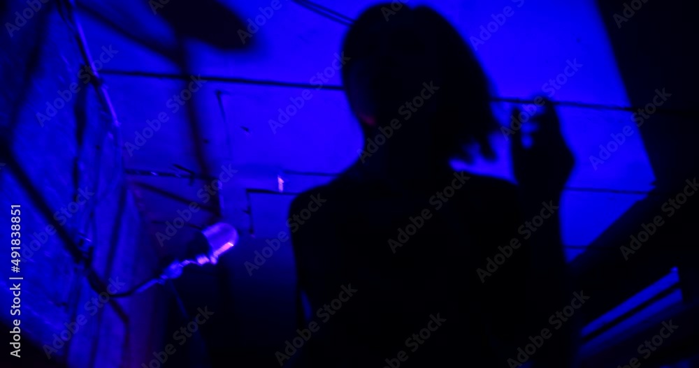 Slow motion low angle shot of scared victim running away from the pursuer. The witness of illegal fights is trying to hide in the dark corners of an underground club
