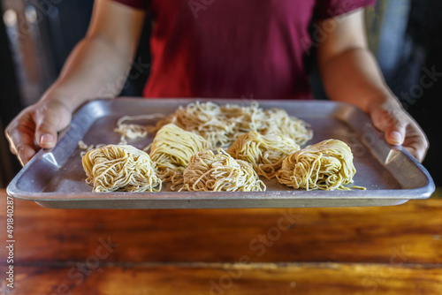 Yellow noodles in the chef's hand on the table