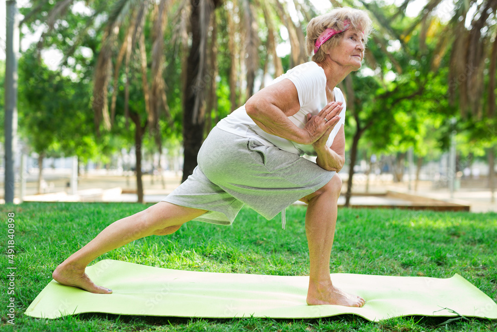 Old lady standing in yoga pose outdoors