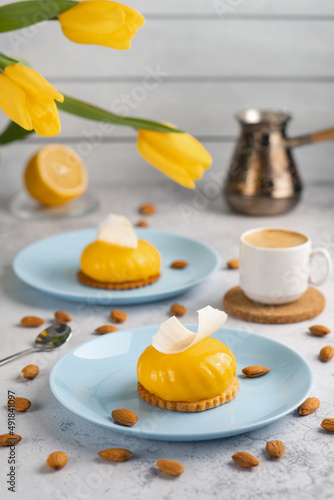Yellow cupcakes and cup of coffee with yellow tulips on concrete background. Tasty morning dessert