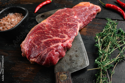 Raw Grass Fed NY Strip Steaks with Salt and Pepper, on old dark  wooden table background