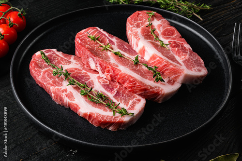 Fresh pork neck meat steaks, on black wooden table background