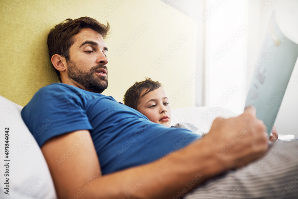 Fototapeta premium Nobody does story time like dad does. Shot of a young man reading a book with his son at home.