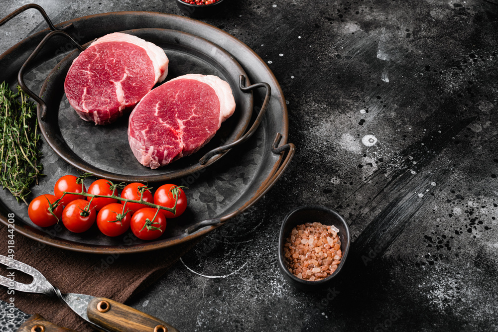 Fresh raw organic beef steak, on black dark stone table background, with copy space for text