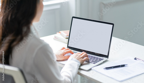 Image of young Asian business woman using laptop with blank screen
