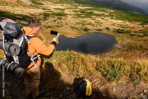 Tourist sits on the grass high in the mountains on the background of Lake Nesamovite, tourist and Lake Nesamovite, autumn scenery near the lake. photo