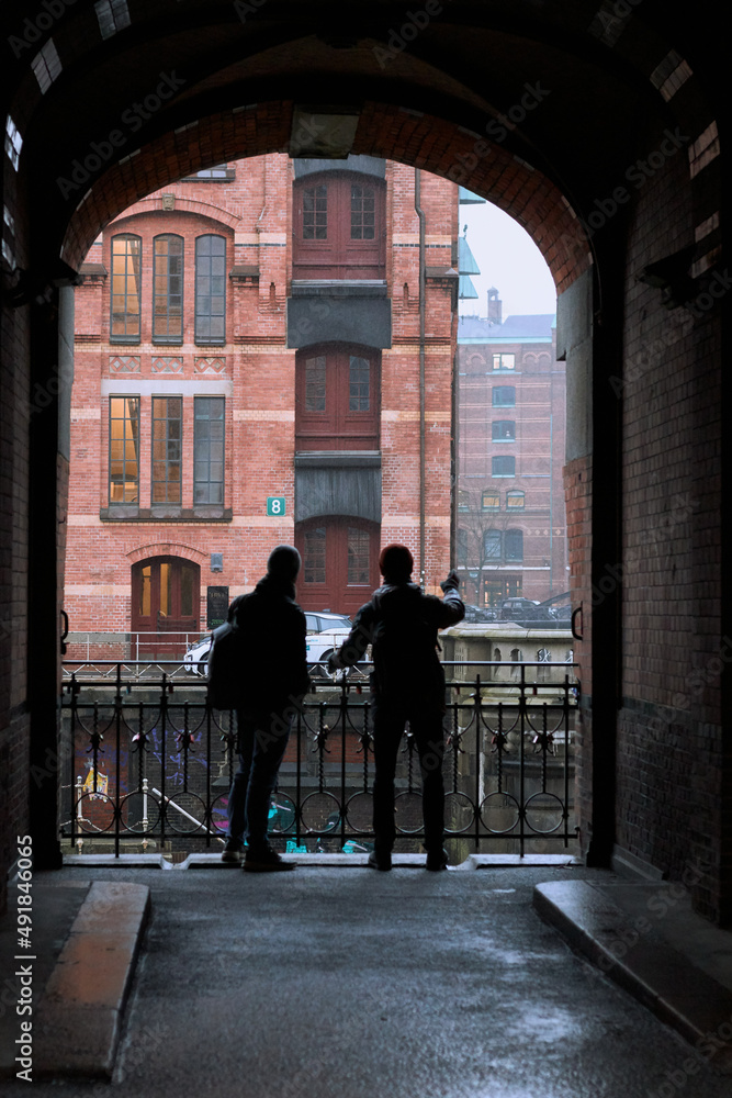 Back view of young tourists with backpacks looking at beautiful architecture of old city Hamburg