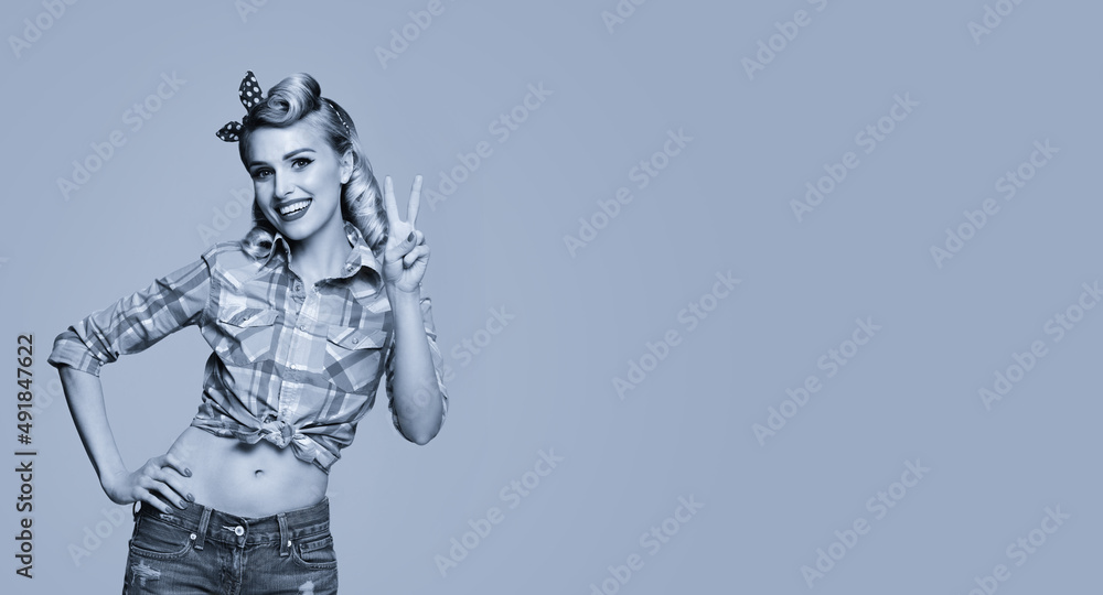 Portrait of beautiful young happy smiling woman, showing two fingers or victory gesture, pin up style. Caucasian blond girl posing in retro fashion and vintage concept. Black and white. Copy space. Portrait of beautiful young happy smiling woman, showing two fingers or victory gesture, pin up style. Caucasian blond girl posing in retro fashion and vintage concept. Black and white. Copy space.