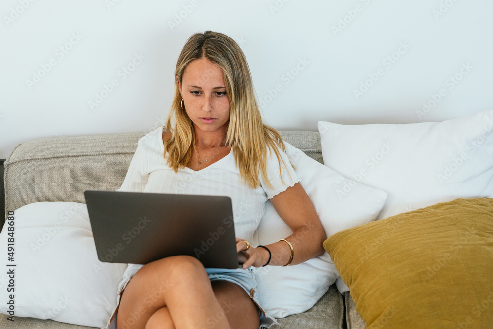 Woman browsing laptop on couch Woman browsing laptop on couch