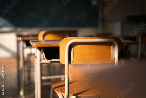 Empty Japanese school classroom with wooden chairs, desks, and a chalkboard. 