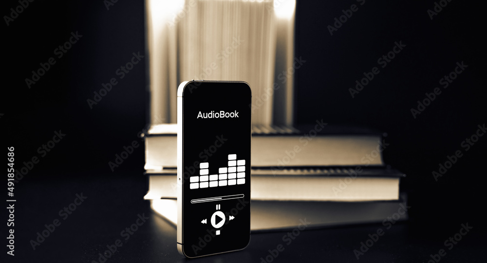 Audiobooks concept. Smartphone screen with audiobook application on paper books black background. Concept of education, library, students.