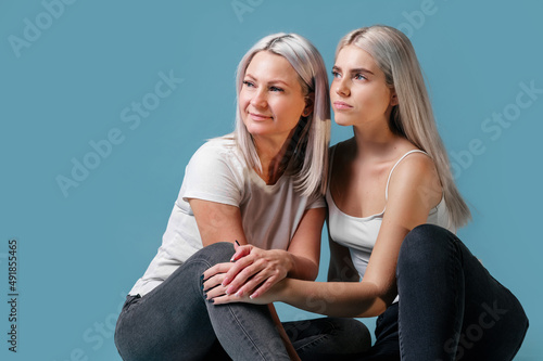 Blondehaired Mom and teenager daughter smiling on colorful backgroung. studio shoot with copy space photo
