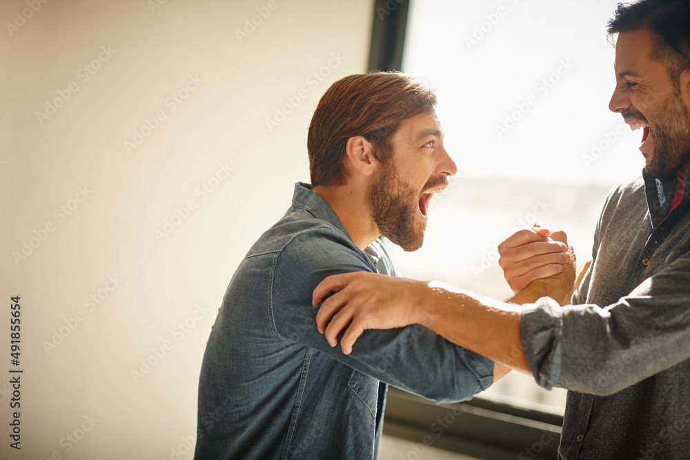 Obraz premium This is the hard work behind the dream. Shot of two businessmen shaking hands together and shouting in celebration while standing in an office.