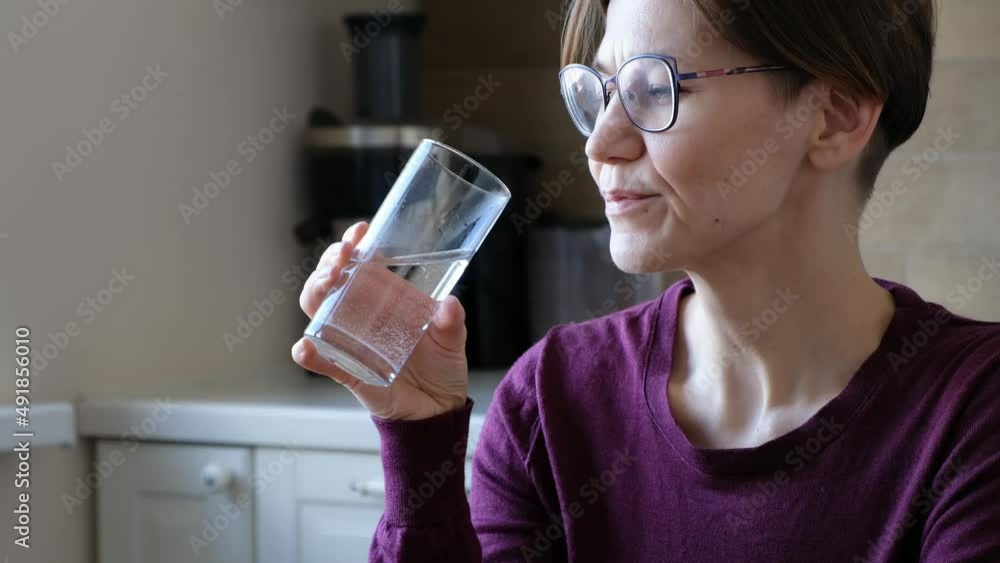 Woman in glasses drinking water in the kitchen, close up Woman in glasses drinking water in the kitchen, close up