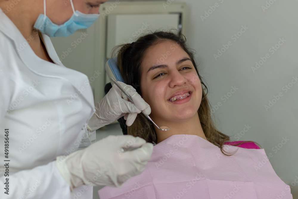 Smiling teenager girl with braces having dental treatment at dentist's office Smiling teenager girl with braces having dental treatment at dentist's office