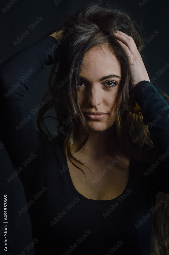Portrait of a beautiful long-haired Italian woman who, with her hands on her head, has an intense and seductive gaze Portrait of a beautiful long-haired Italian woman who, with her hands on her head, has an intense and seductive gaze