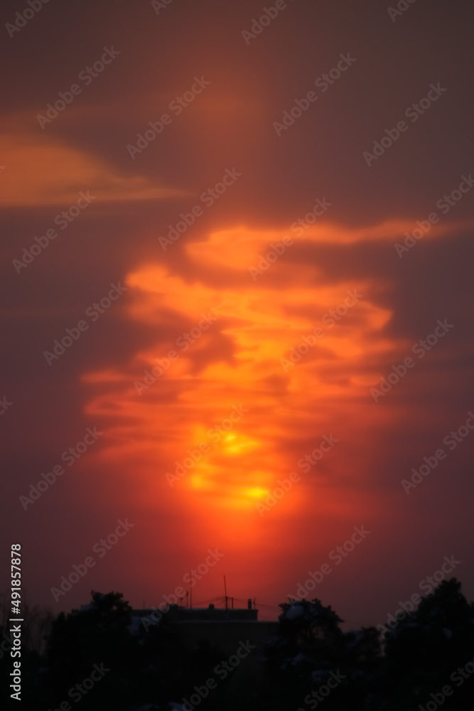 Sun behind the cloud at sunset bonfire-like vertical photo