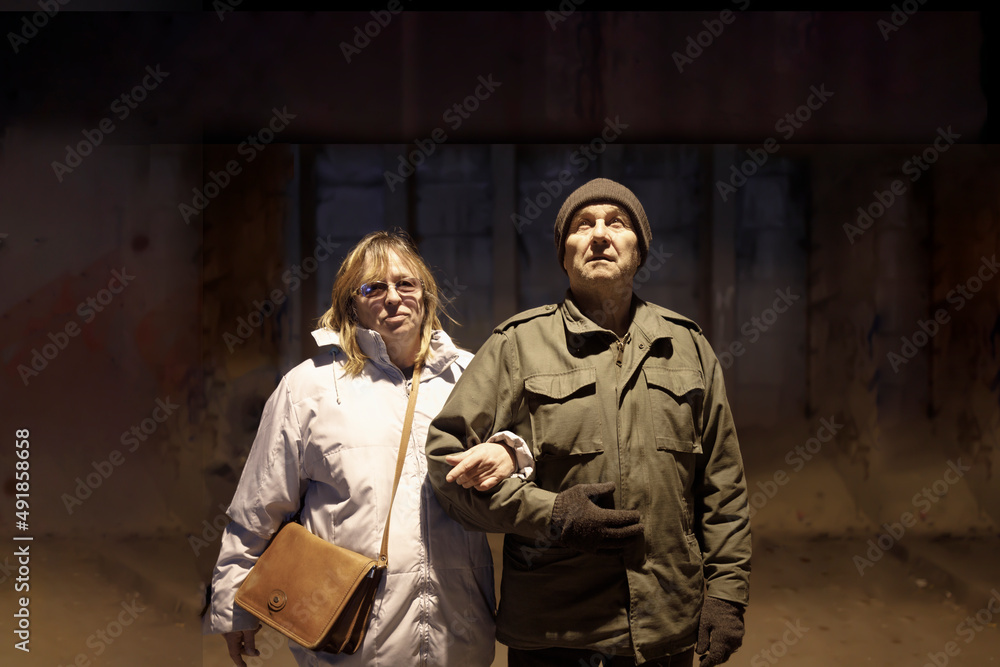 Elderly wife and husband standing together in a nuclear shelter