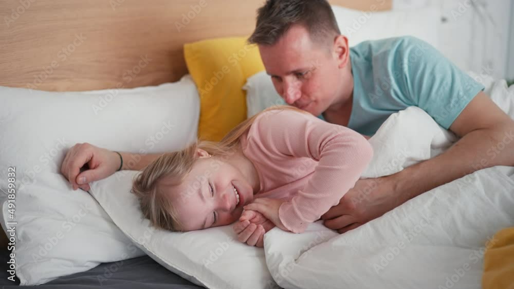Father resting with his little daughter with Down syndrome in bed at home. Father resting with his little daughter with Down syndrome in bed at home.