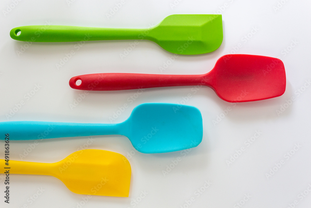Silicone spatulas in various color, red, blue, green and yellow lay on white background Silicone spatulas in various color, red, blue, green and yellow lay on white background