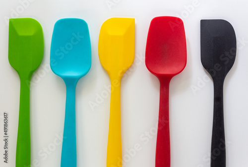 Silicone spatulas in various color, red, blue, green and yellow lay on white background photo