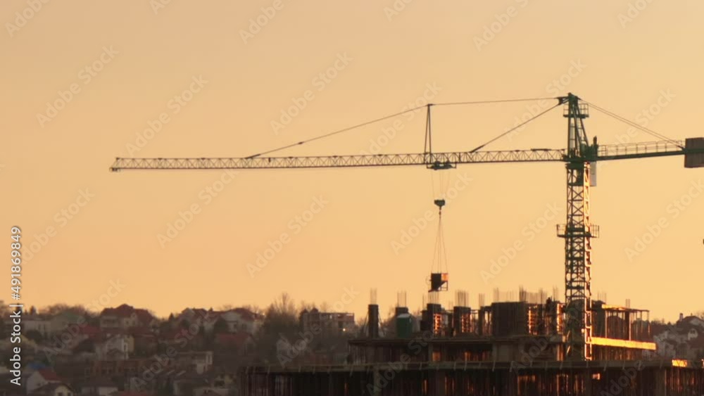 Construction workers at a building site with crane at sunset Construction workers at a building site with crane at sunset