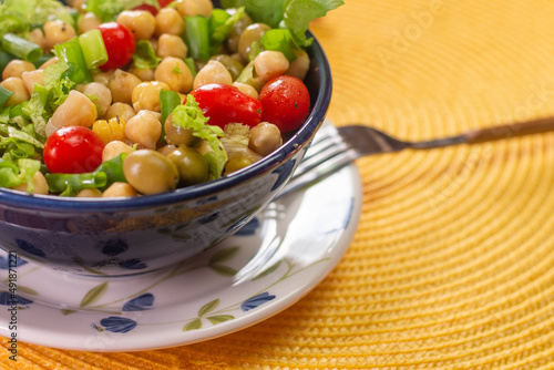  chickpeas with leaves, olives and tomatoes in a blue bowl on the table