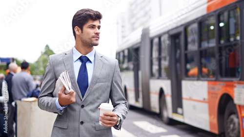 Business on break. A cropped shot of a handsome young man walking in the city holding coffee and a newspaper. photo