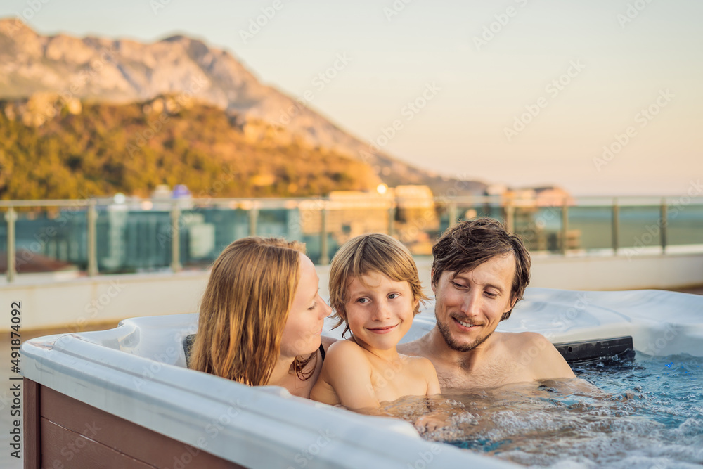 Portrait of young carefree happy smiling happy family relaxing at hot tub during enjoying happy traveling moment vacation. Life against the background of green big mountains Portrait of young carefree happy smiling happy family relaxing at hot tub during enjoying happy traveling moment vacation. Life against the background of green big mountains