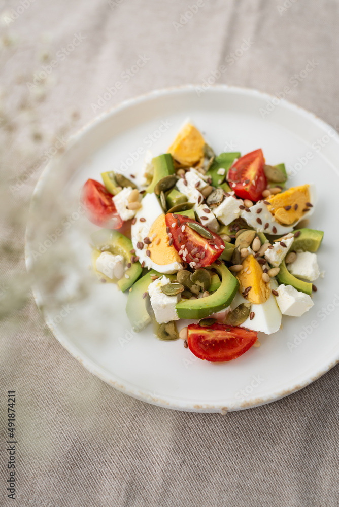 Healthy egg and avocado salad. Salad for breakfast with tomato, avocado, feta, pine nuts, sesame, flax seeds and boiled egg on a concrete background Healthy egg and avocado salad. Salad for breakfast with tomato, avocado, feta, pine nuts, sesame, flax seeds and boiled egg on a concrete background