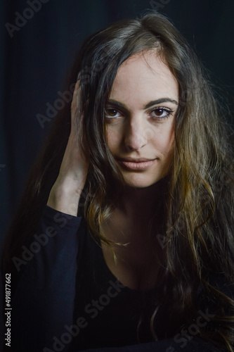 portrait of a beautiful Italian girl with long hair with her hand in her hair with a seductive look