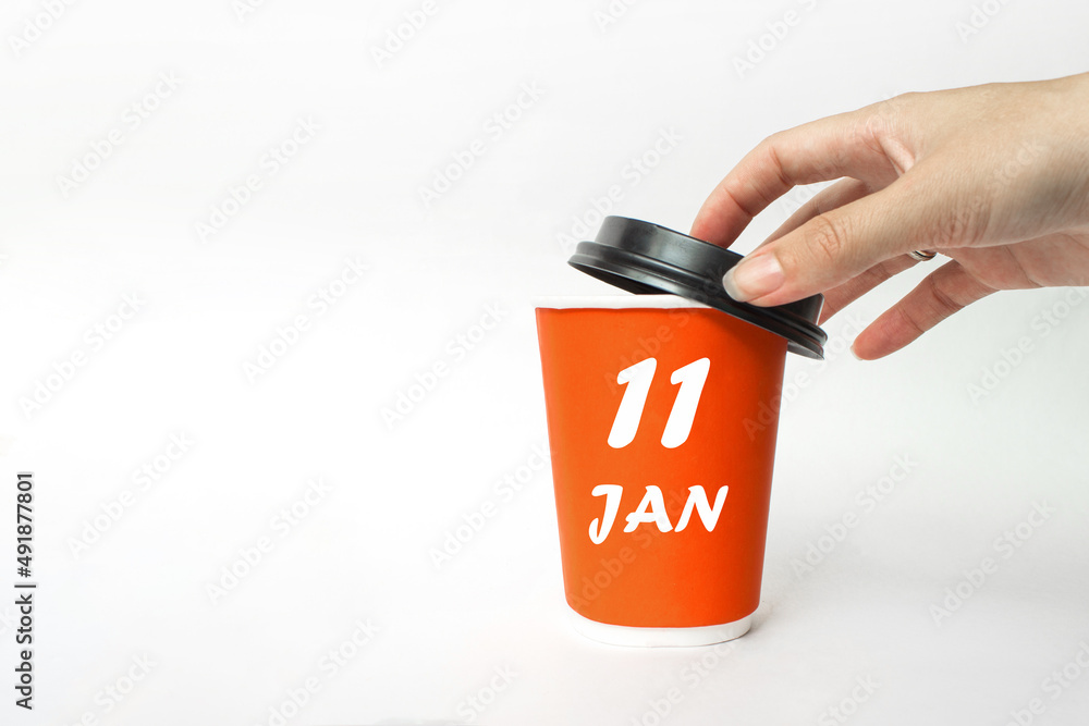 January 11st . Day 11 of month, Calendar date. A woman's hand open black plastic cap of red disposable cardboard coffee paper cup with Calendar Date. Winter month, day of the year concept. January 11st . Day 11 of month, Calendar date. A woman's hand open black plastic cap of red disposable cardboard coffee paper cup with Calendar Date. Winter month, day of the year concept.