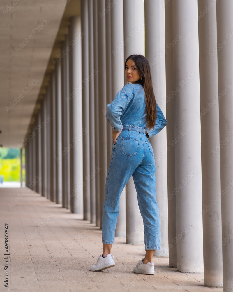 Fototapeta premium Young caucasian girl with a monkey cowboy next to a white columns. Enjoying the city on vacation, lifestyle of a young girl in a fashionable poster