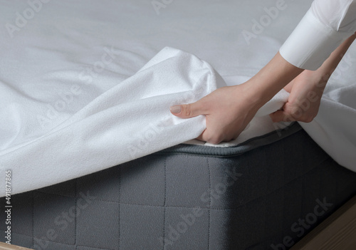 A young girl puts on a mattress pad. Girl changing bed linen