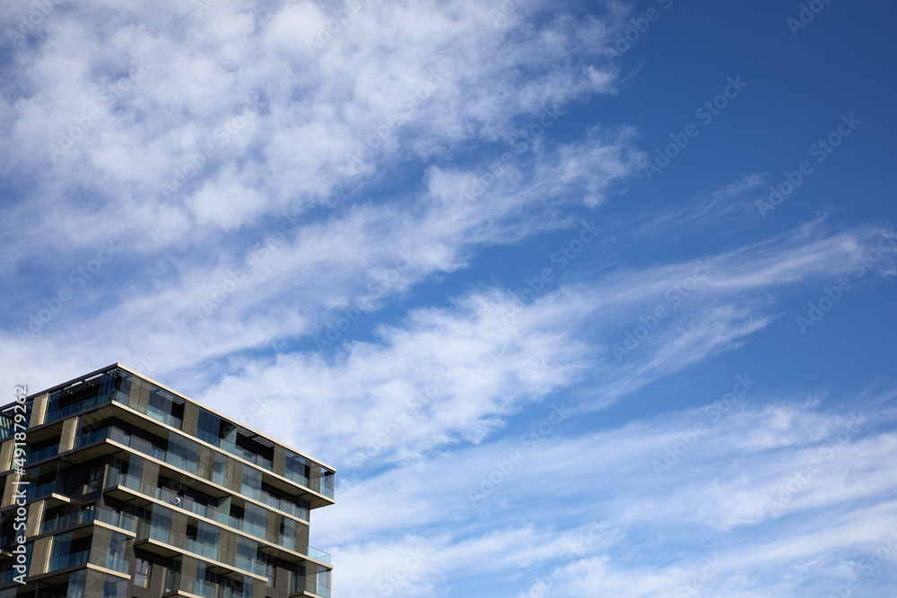 Nowoczesny apartamentowiec na tle błękitnego nieba z chmurami - obrazy, fototapety, plakaty 