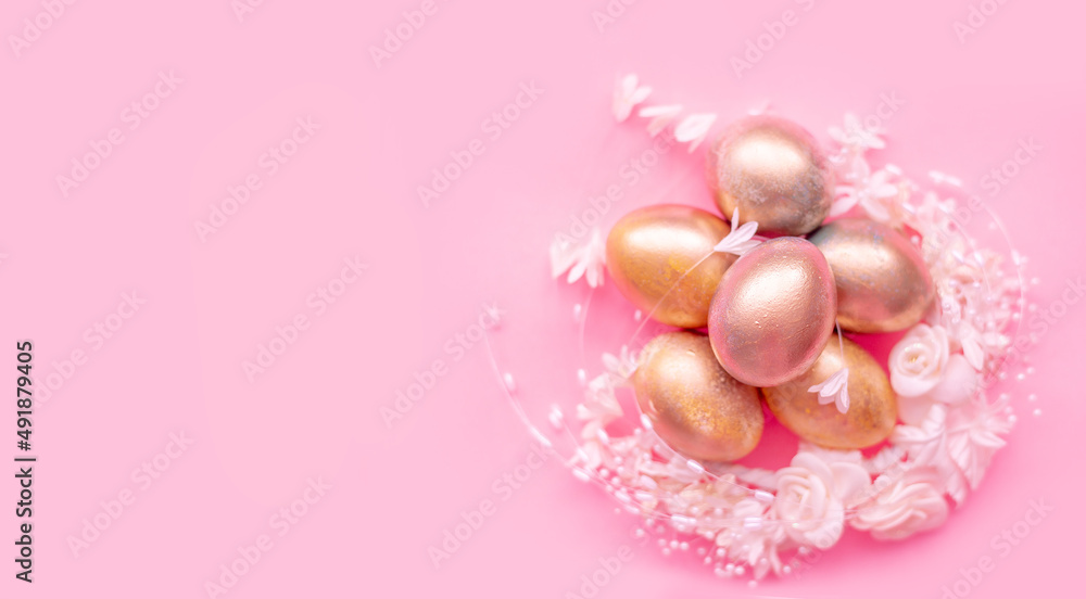 Golden eggs in a flower nest on a pink background . Easter concept with space for text Golden eggs in a flower nest on a pink background . Easter concept with space for text