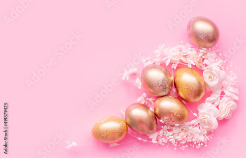 Golden eggs in a flower nest on a pink background . Easter concept with space for text
