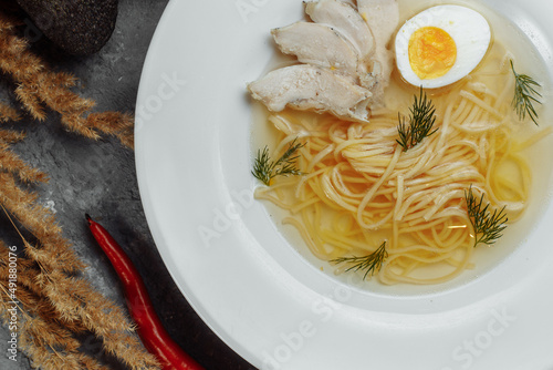 Chicken soup with noodles and vegetables in white bowl