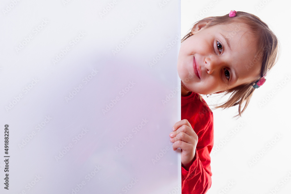 Young beautiful child girl looking behind white empty banner. Free copy space for text or design. Young beautiful child girl looking behind white empty banner. Free copy space for text or design.