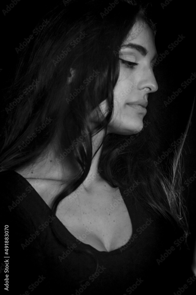 Naklejka premium Black and white portrait of a beautiful Italian girl with long hair in profile looking down