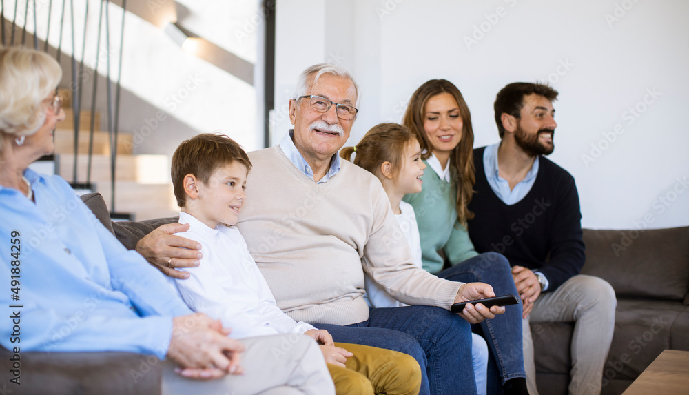 Multi generation family sitting together on the sofa at home and watching TV