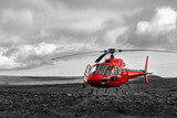 Red Helicopter landed near Thrihnukagigur Volcano in Iceland on a Lava field near Bláfjöll Country Park and Reykjavik for tourists. Modern aviation in contrast with archaic colorless scenery.