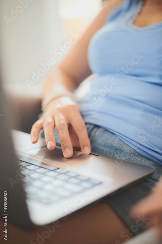 Unrecognizable young adult woman using the trackpad of her laptop while works from home wearing casual clothes. Real people concept.