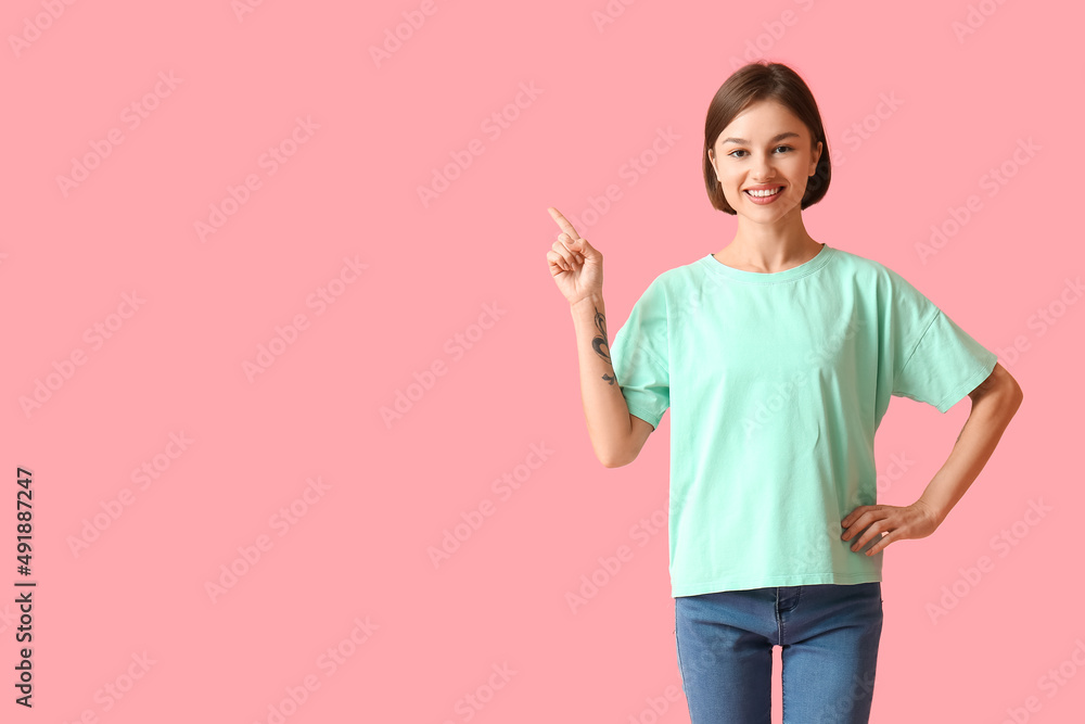 Beautiful young woman in stylish t-shirt pointing at something on color background Beautiful young woman in stylish t-shirt pointing at something on color background