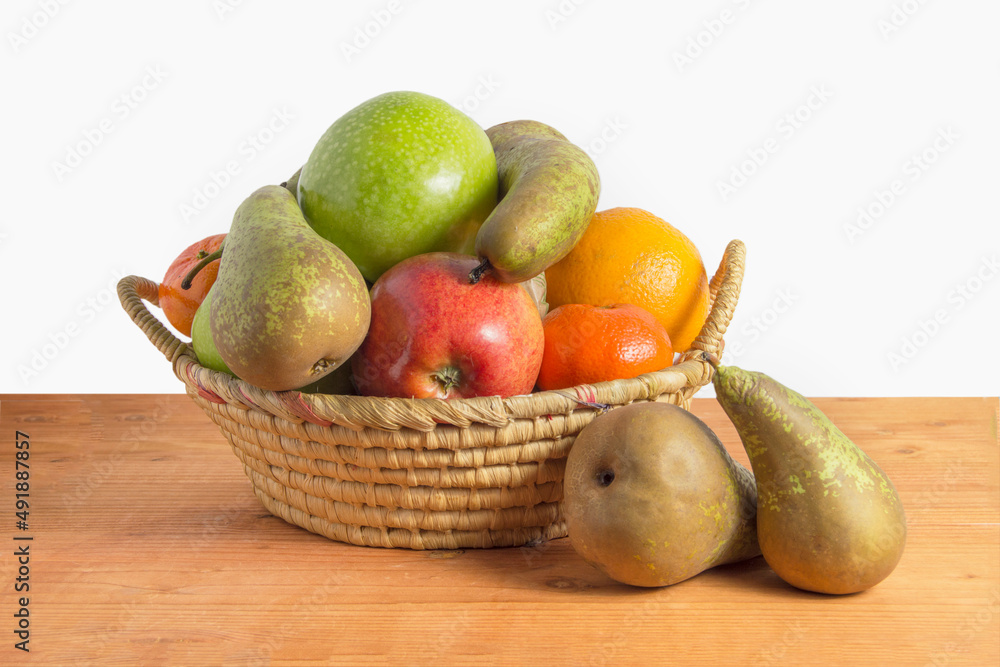 basket  with pears, apples, oranges and tangerines on wood and white background